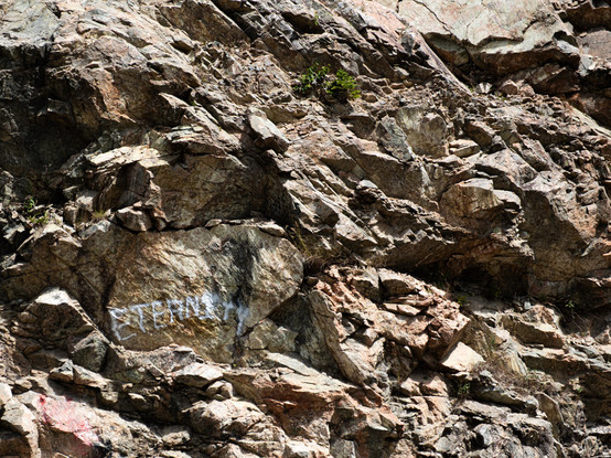 A rough rockface with white-spraypaint graffiti reading "ETERNITY"