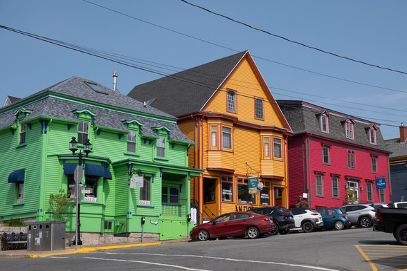 Three houses in Lunenberg, Nova Scotia, brightly colored in green, orange, and violet-red.