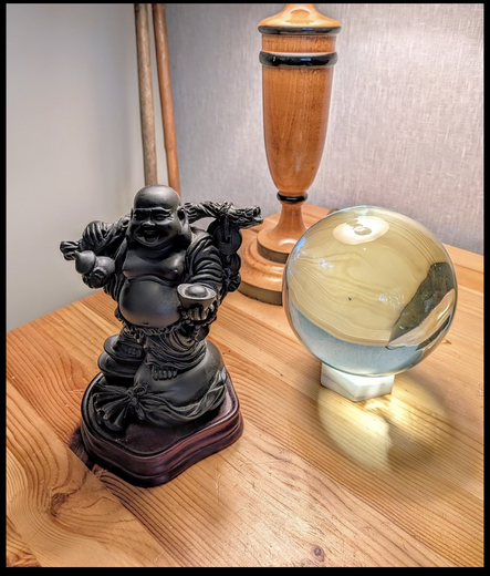 Photograph taken with a Google Pixel 10 of objects on a desktop: A small black statuette of Budai, a crystal ball, and the base of a wooden lamp. Two wooden shafts appear in the background, but their nature is a mystery.

The photo has been edited using Google's Magic Erase and that fact is disclosed in its Content Credentials.