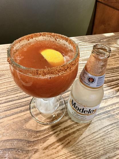 After, the beer is mixed with tomato juice and a lemon wedge is floating, empty beer bottle to the side. 